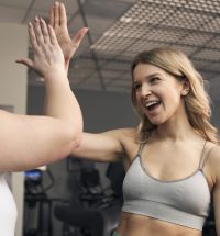 Caucasian women high five together at the gym